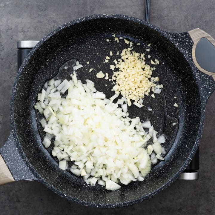 Chopped onion and garlic sizzling in oil in a pan over medium heat.