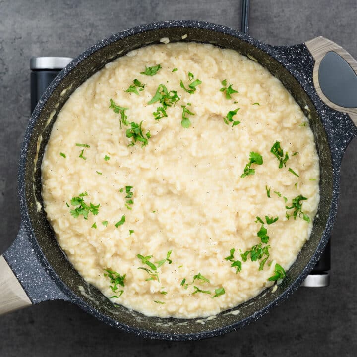 Risotto garnished with freshly chopped parsley in the pan, ready to be served.