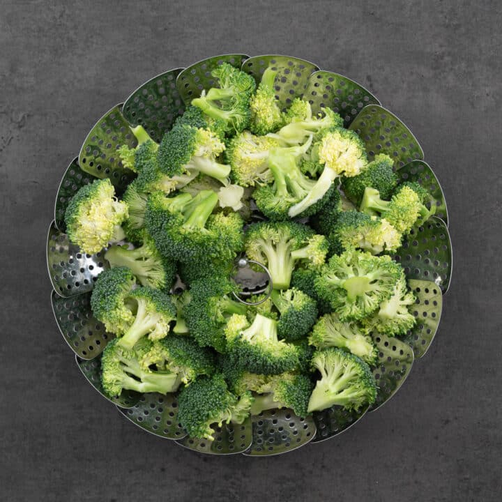 Cleaned broccoli florets neatly arranged in a steamer basket.