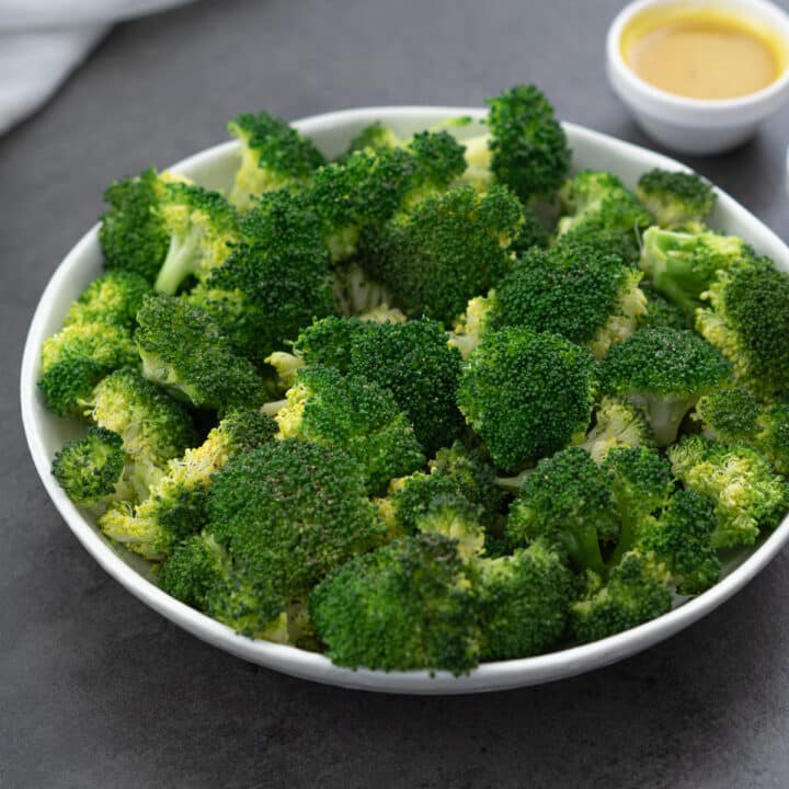 Steamed Broccoli elegantly presented on a white plate, accompanied by a side of honey mustard sauce.