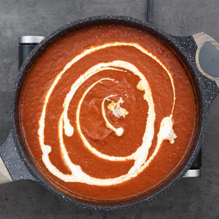 Smooth tomato soup in a pan with heavy whipping cream.
