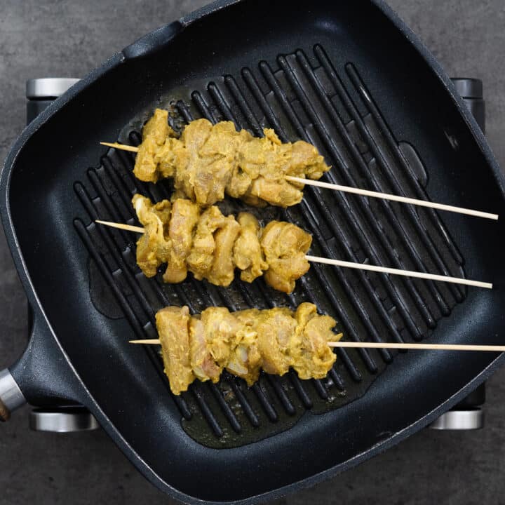Grilling pan with marinated chicken skewers ready for cooking.