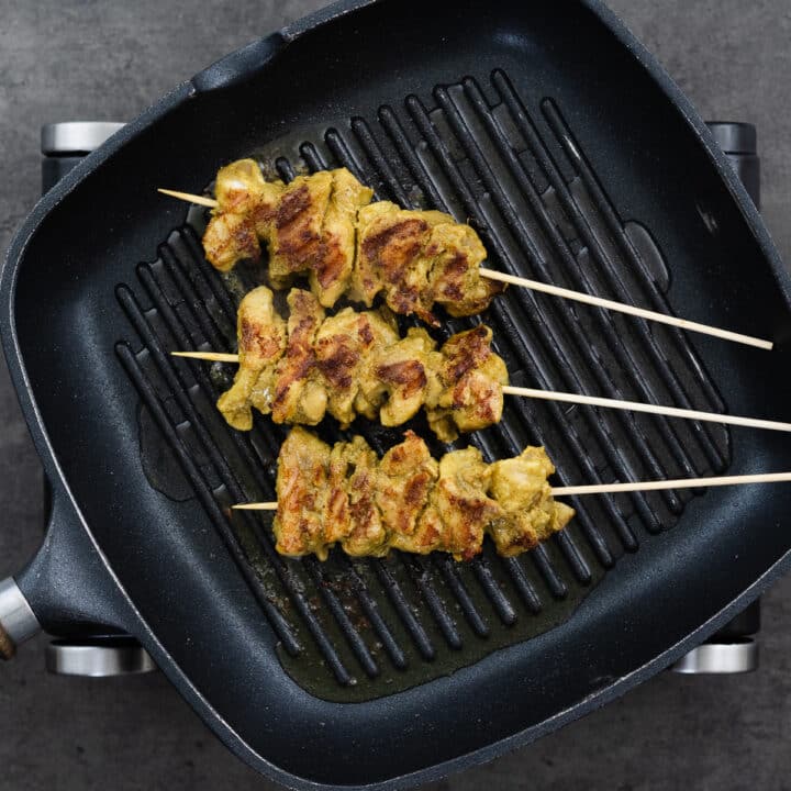 Golden and perfectly charred chicken skewers in the grilling pan.