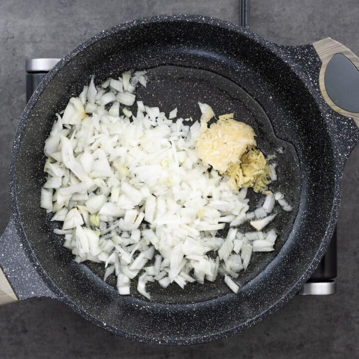 Chopped onion, garlic, and ginger in a pan awaiting sautéing.