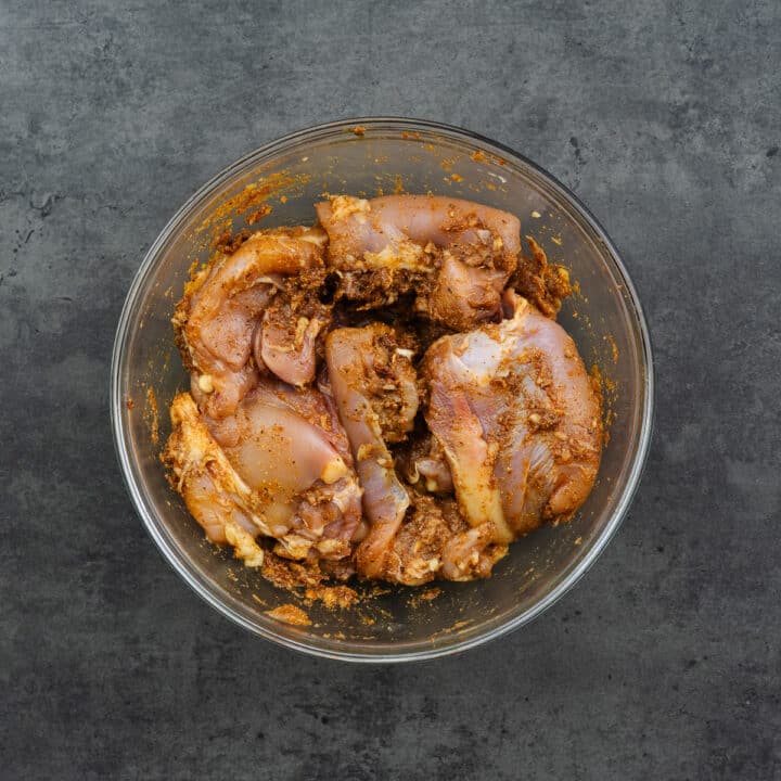 A bowl with chicken thighs marinated in taco marinade.