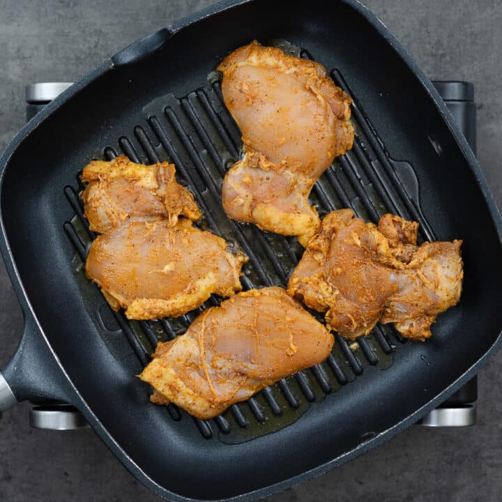 A grill pan with chicken thighs grilling.