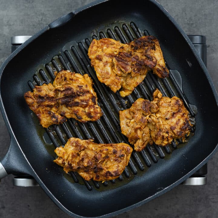A grill pan with chicken thighs grilled to golden brown color.