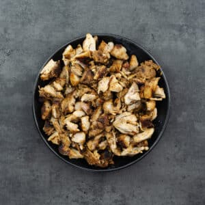 A black plate with diced grilled chicken.