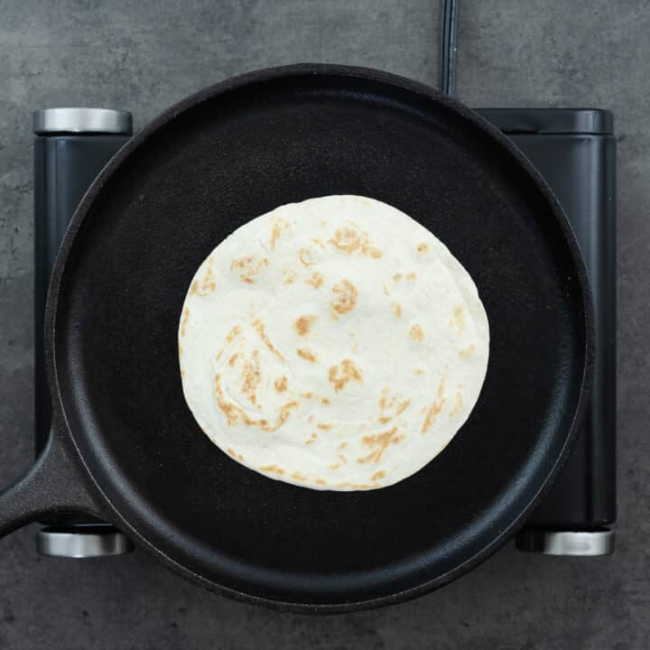A cast iron pan with tortilla being warmed up.
