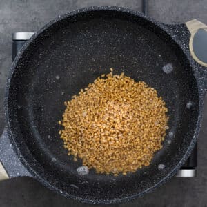 A wide-bottomed pan filled with water and farro.