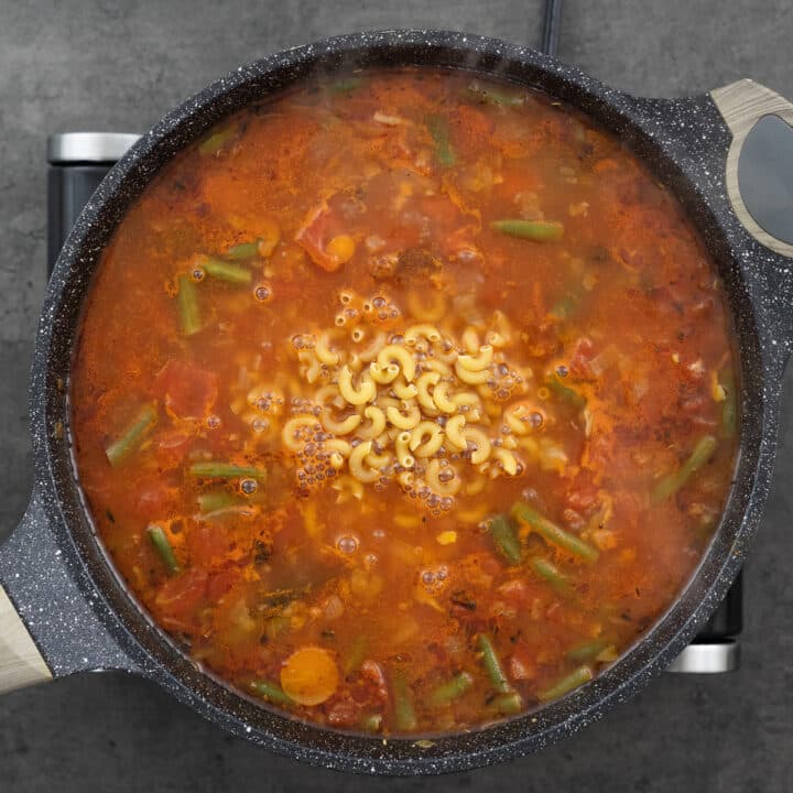 A pan with minestrone soup mixture along with pasta.