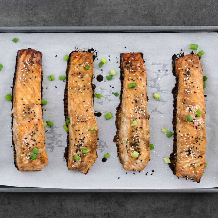 Baked salmon topped with sesame seeds and sliced spring onions.
