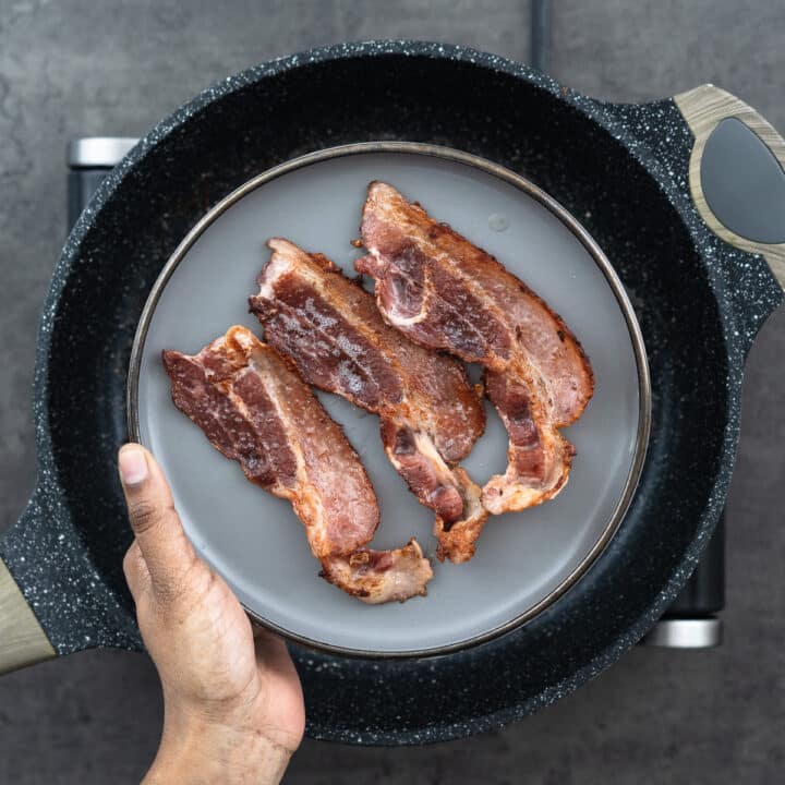 A plate displaying crispy and brown cooked bacon strips.