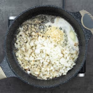 Onions and garlic sautéing in butter in a pan.