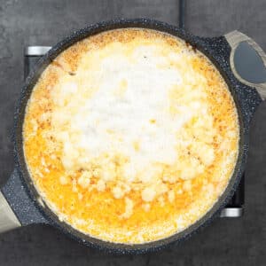 Potatoes cooking in a broth and milk mixture in a pan.