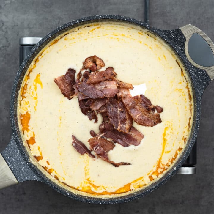 Creamy potato soup with bacon and sour cream in a pan.