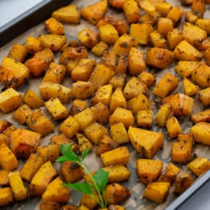 Roasted butternut squash in a baking tray, set on a white table.