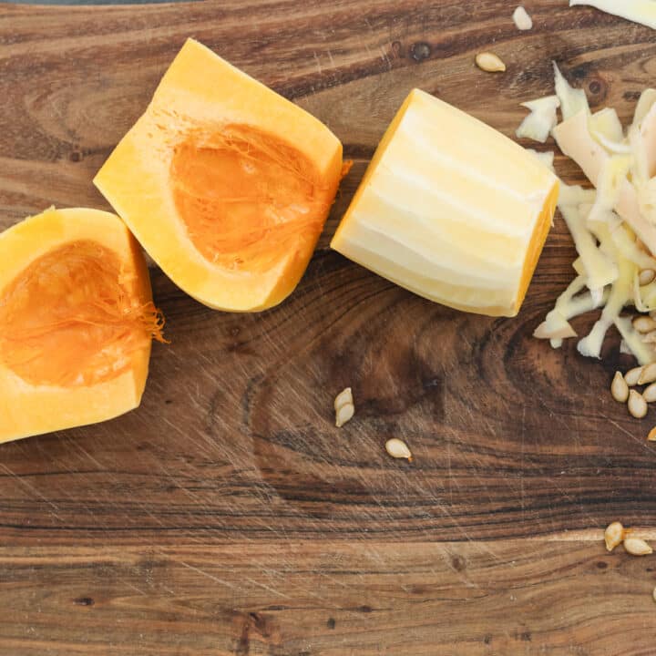 A cutting board with sliced butternut squash with seeds removed.