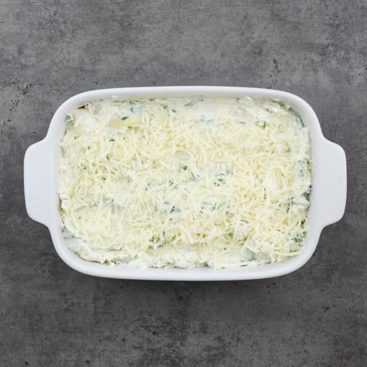 A baking dish filled with spinach artichoke dip mixture.