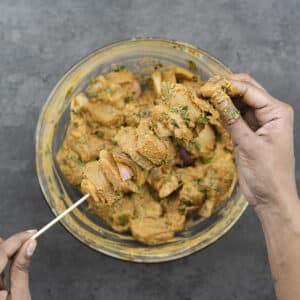 A wooden skewer threaded with chicken and onions.