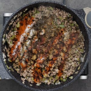 A pot with seasoned ground beef mixture, including chili seasoning and spices.