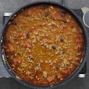 A pot with beef chili mixture simmering in beef broth.
