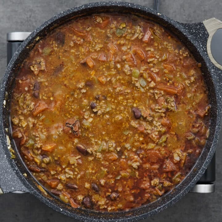 A pot with beef chili mixture simmering on low heat.