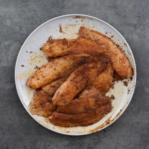Bowl of marinated tilapia fillets.