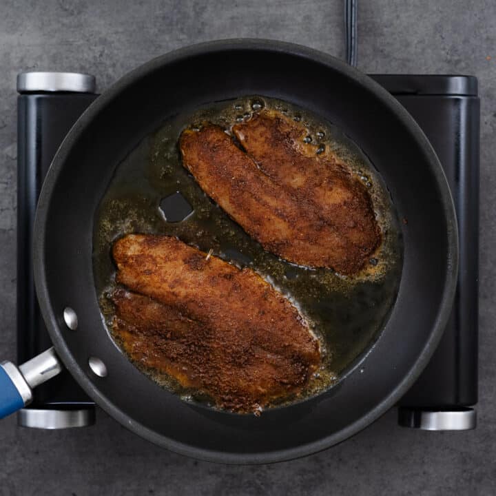 Pan with tilapia fillets frying.
