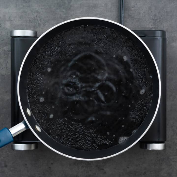 Black rice boiling rapidly in a pot of water.