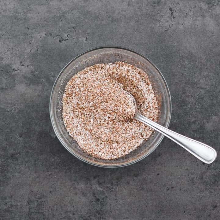 A bowl filled with homemade seasoned salt, ready to be used, accompanied by a spoon.