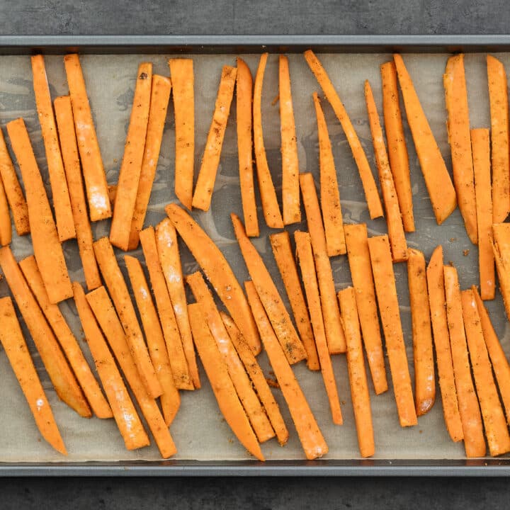 Sliced sweet potato arranged neatly on a parchment-lined baking tray.