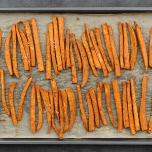 Sweet potato fries in a baking tray seasoned with salt.