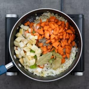 A pot with hard vegetables, bay leaves, dried thyme, and salt.