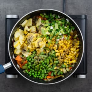 A pot with hard and soft vegetables seasoned with curry powder and black pepper.