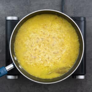 Rice cooking in spice infused water in a pan.