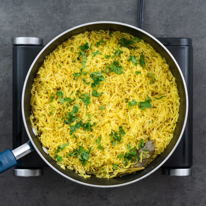 A pan with Yellow Rice garnished with cilantro leaves.
