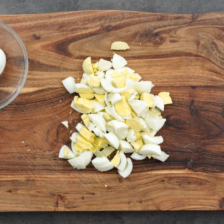 Chopped boiled eggs on a wooden cutting board.