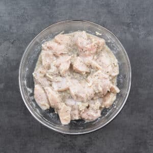 A bowl with boneless chicken marinated in a souvlaki marinade.