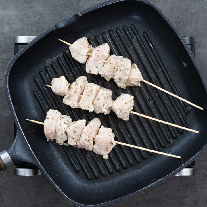 A grill pan with chicken on skewers.