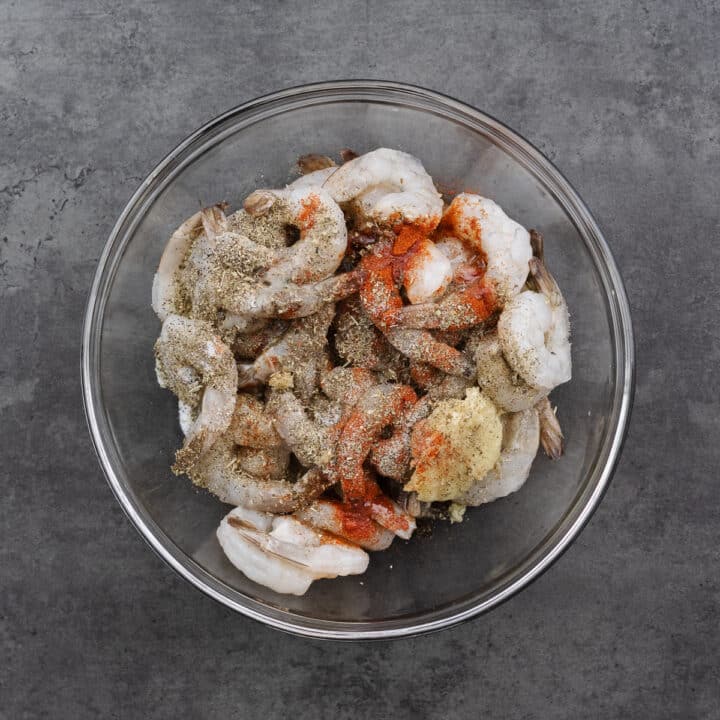 A bowl with shrimp and marinating ingredients.