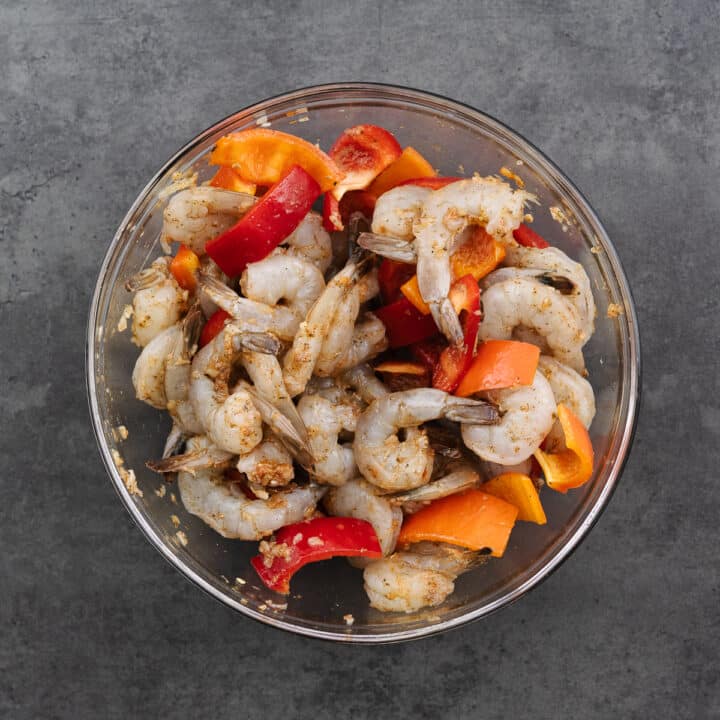 A bowl with marinated shrimp and bell peppers.