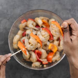 A wooden skewer with shrimp and bell peppers.