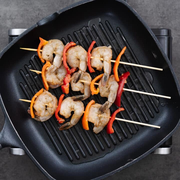 A grill pan with shrimp skewers.