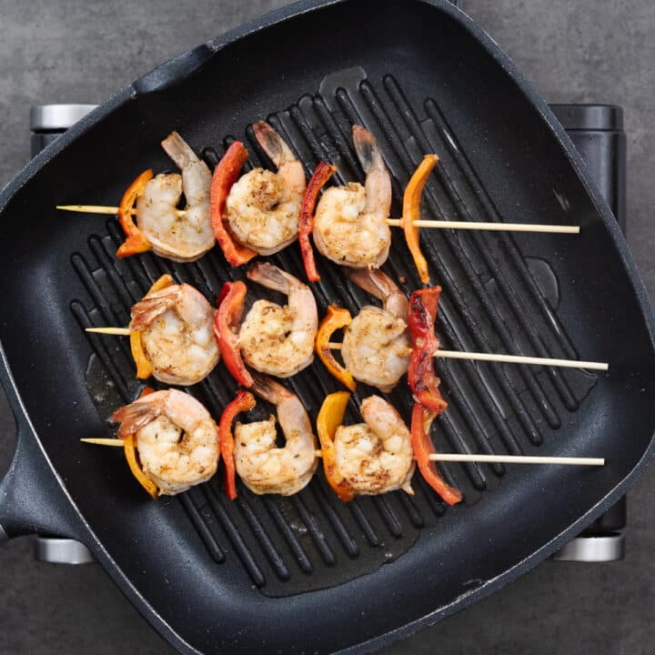 A pan with shrimp skewers grilling in a pan.
