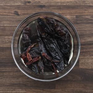 A bowl with dried red chilies soaking in hot water.