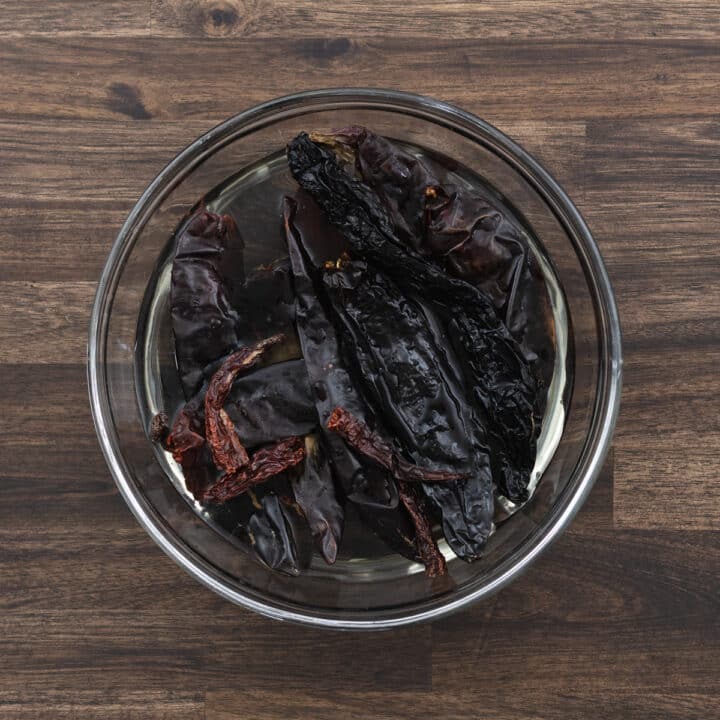 A bowl with dried red chilies soaking in hot water.