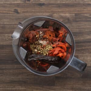A blender jar filled with harissa ingredients.