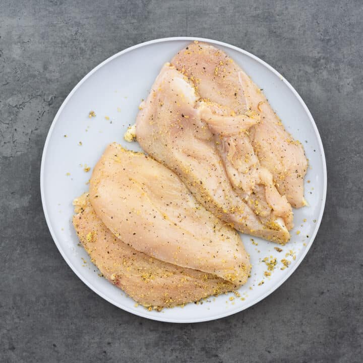 Thinly sliced chicken breast seasoned with lemon pepper seasoning on a plate.