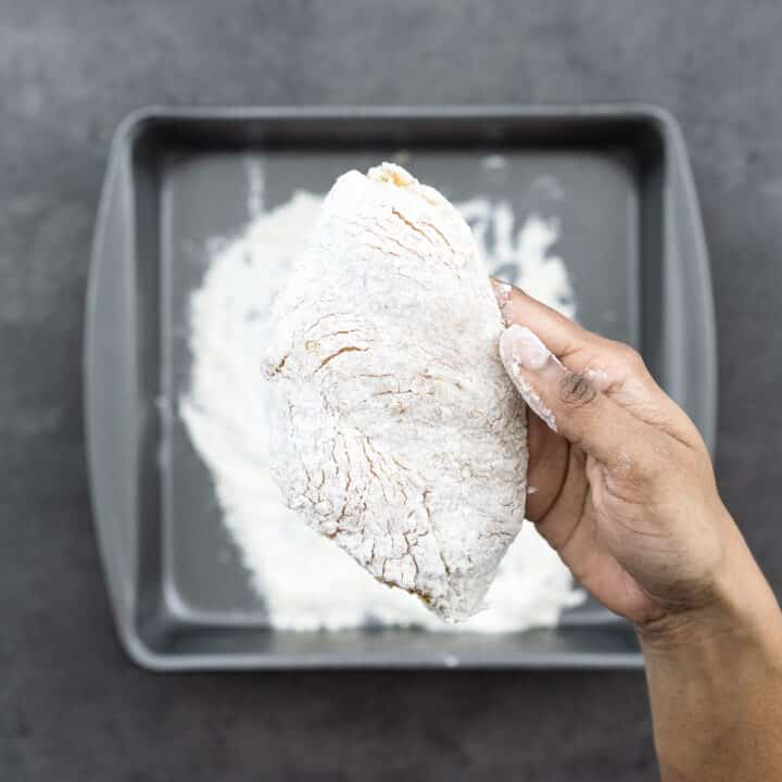 Close-up of lemon pepper seasoned chicken breast coated in flour.